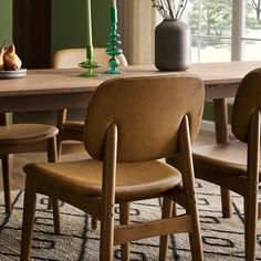 a dining room table with chairs and vases on it's centerpiece in front of a window