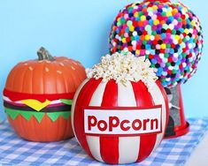 two pumpkins with popcorn on them sitting next to each other in front of a blue wall