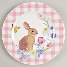 a pink and white plate with a rabbit on it's side surrounded by flowers