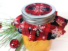 a jar filled with jam sitting on top of a table next to christmas decorations and pine branches