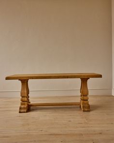 a wooden bench sitting on top of a hard wood floor next to a white wall