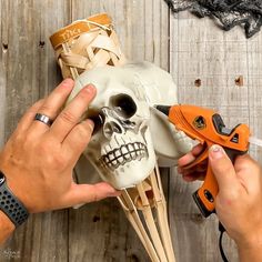 a man is working on a skull with pliers and wire cutters next to it