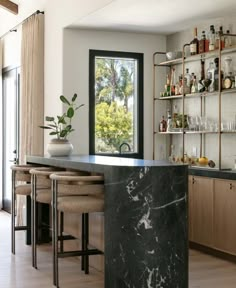 a kitchen with marble counter tops and bar stools in front of an open window