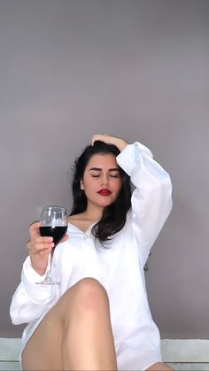 a woman sitting on the floor holding a glass of wine