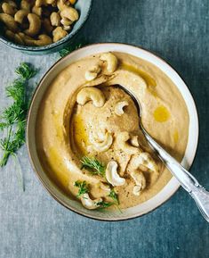 a bowl filled with hummus and cashews on top of a table