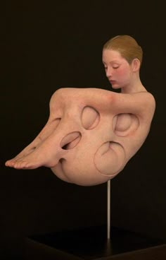 a woman is sitting on top of a fake human body, with her eyes closed