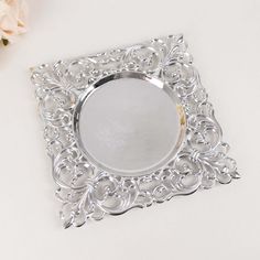 a silver tray with a flower on the side and a white rose in the background