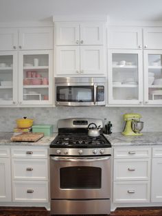 a stainless steel stove top oven sitting inside of a kitchen next to white cupboards