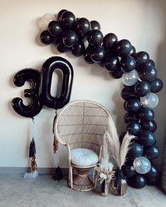 balloons and decorations are arranged on the floor in front of a balloon arch that reads 30