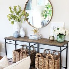 a living room filled with furniture and a large round mirror above the console table on top of it