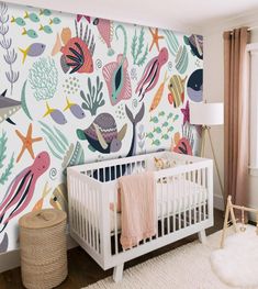 a baby's room with colorful wallpaper and a white crib in the foreground