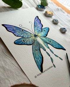 a blue butterfly is sitting on top of a piece of paper