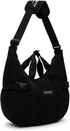 Water-repellent nylon canvas messenger bag in black. · Webbing trim throughout · Press-stud tab at fixed carry handles · Strap pad at shoulder strap · Logo patch at face · Press-release tab at sides · Zip pocket at interior · Moiré lining · H10.5 x W14.5 x D4.5 Supplier color: Black Carhartt Messenger Bag, Carhartt Work In Progress, Crossbody Bags For Travel, Nylon Tote Bags, Cute Handbags, Canvas Messenger Bag, Nylon Tote, Fabric Bag, Press Release