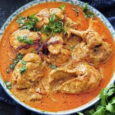 a bowl filled with chicken curry and garnished with cilantro