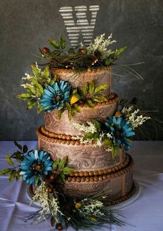 a three tiered cake with blue flowers and greenery