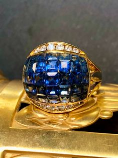 Not your average dome ring! This piece is crafted in heavy 18K yellow gold and set with approximately 7cttw in calibrated square cut natural royal blue sapphires as well as .40cttw in round cut G-I color Vs1-Si1 clarity round diamonds. Dimensions/Weight: Ring measures .70" by .70" and weighs 11.1g. Size 7 (sizable). Condition: All stones are secure and in perfectly wearable condition. R-RKLL Luxury Cushion Cut Sapphire Ring With Vvs Clarity, Luxury Sapphire Birthstone Ring For Formal Occasions, Luxury Sapphire Cluster Ring, Luxury Sapphire Birthstone Ring, Luxury Cushion Cut Sapphire Ring, Elegant Domed Sapphire Ring For Formal Events, Luxury Blue Sapphire Ring With 17 Jewels, Luxury Dome Ring With Diamond Cut For Formal Occasion, Luxury Dome Ring With Diamond Cut For Formal Events