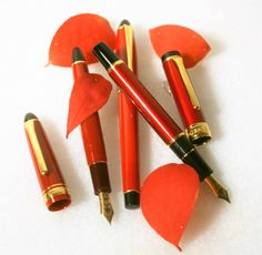 four red and black pens sitting next to each other on top of a white surface