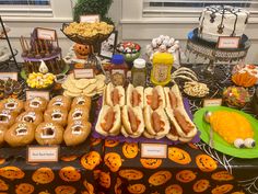 a table topped with lots of hot dogs on buns covered in toppings and candy