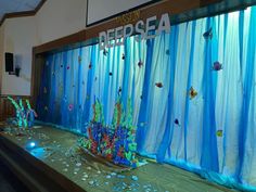 an ocean themed stage set up with blue drapes and sea creatures on the curtain