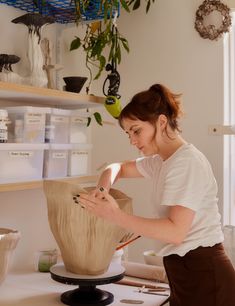 a woman is working on a vase in her home studio, making it look like something out of clay