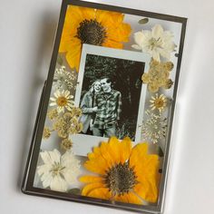 a photo frame with flowers and a couple in the middle is shown on a table