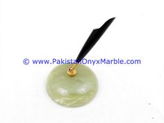 a pen sitting on top of a green jade ball with a black handle and gold accents