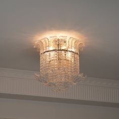 a chandelier hanging from the ceiling in a room with white walls and trimmings