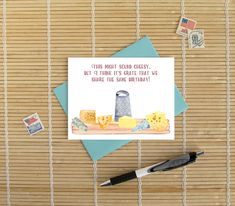 a greeting card with some type of cheese on it, next to a fountain pen