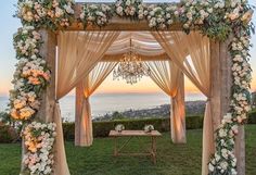 the wedding arch is decorated with flowers and greenery for an outdoor ceremony at sunset