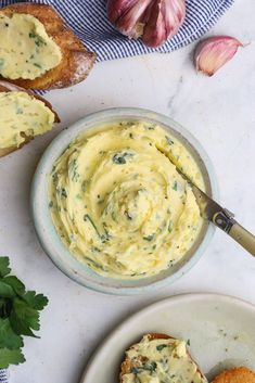 a plate with bread, garlic and spread on it next to garlic cloves