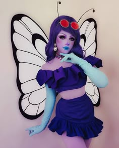 a woman dressed as a butterfly with purple hair and makeup