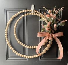 a wooden beaded wreath with flowers and ribbon hanging on the front door for an easy diy project