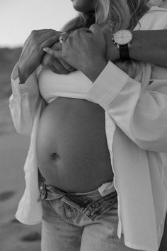 a black and white photo of a pregnant woman holding her baby bump in the belly