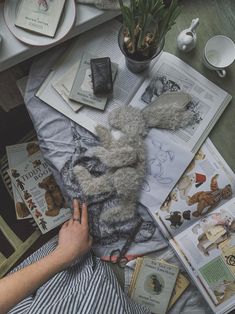 a person holding a stuffed animal on top of a table next to books and magazines