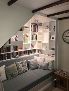 a living room filled with lots of furniture and bookshelves next to a stair case