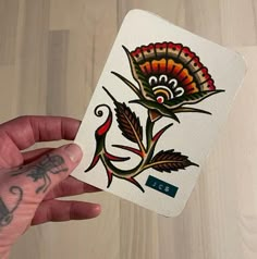 a hand holding up a small card with an image of a flower on the front