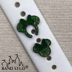 two green and gold glittered mickey mouse ears are on top of a white guitar picker