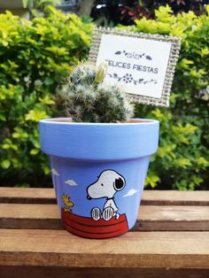 a small potted plant with a snoopy dog on it sitting on a wooden table