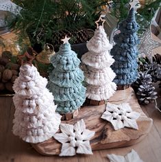 small knitted christmas trees sitting on top of a wooden table next to pine cones