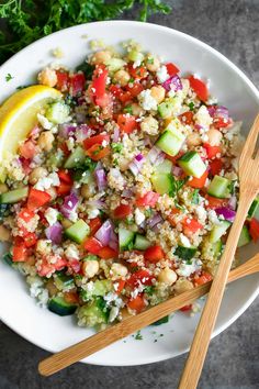 a white bowl filled with salad and two wooden chopsticks on top of it