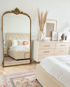 a bedroom with a bed, dresser and large mirror in front of the bed is shown