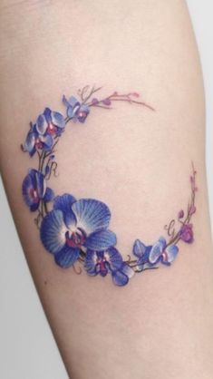 a blue and purple flower tattoo on the side of a woman's thigh,