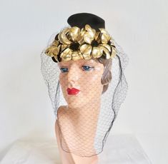 Lovely eye catching formal hat from the 1940's. Made in black felt in a brimless Toque style. Adorned with 4 firm metallic flowers (feels like a thick, firm vinyl) with black felt centers at the front edge. gold cord ties at the back of the hat. Also trimmed with a black face veil. Interior hat is trimmed with a black grosgrain ribbon band. **Ask me about International shipping rates. Label:  New York Creation Condition:  Excellent.  Looks barely worn if at all.  Veil intact. Size/Measurements:  No size label.   crown height-  4.5" diameter-  7" inside crown-  21.25" Metallic Flowers, Formal Hat, Face Veil, Cord Ties, Lovely Eyes, Size Label, Black Felt, Gold Flowers, Grosgrain Ribbon