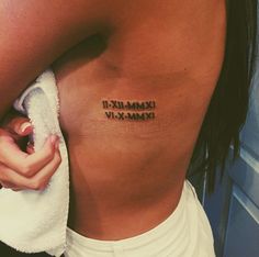 a woman's lower back tattoo with roman numerals on her left side