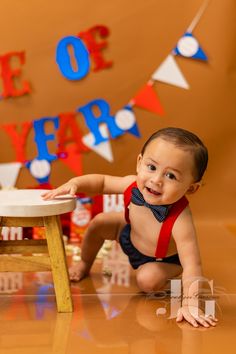 a baby is sitting on the floor in front of a table and some decorations that say happy new year