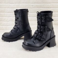 a pair of black leather boots with straps and buckles on the side, sitting on a white carpet