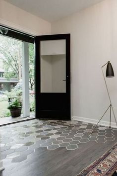 an empty room with a rug, floor lamp and large glass door leading to the outside