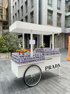 a white cart with oranges on it sitting in the middle of a street next to tall buildings