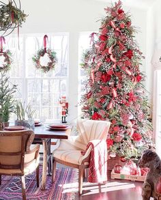 a decorated christmas tree in the corner of a room with chairs and a rug on the floor