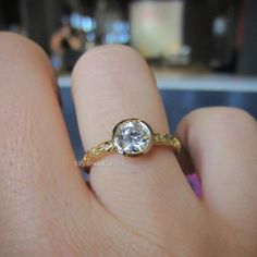 a woman's hand with a ring on it that has a diamond in the middle